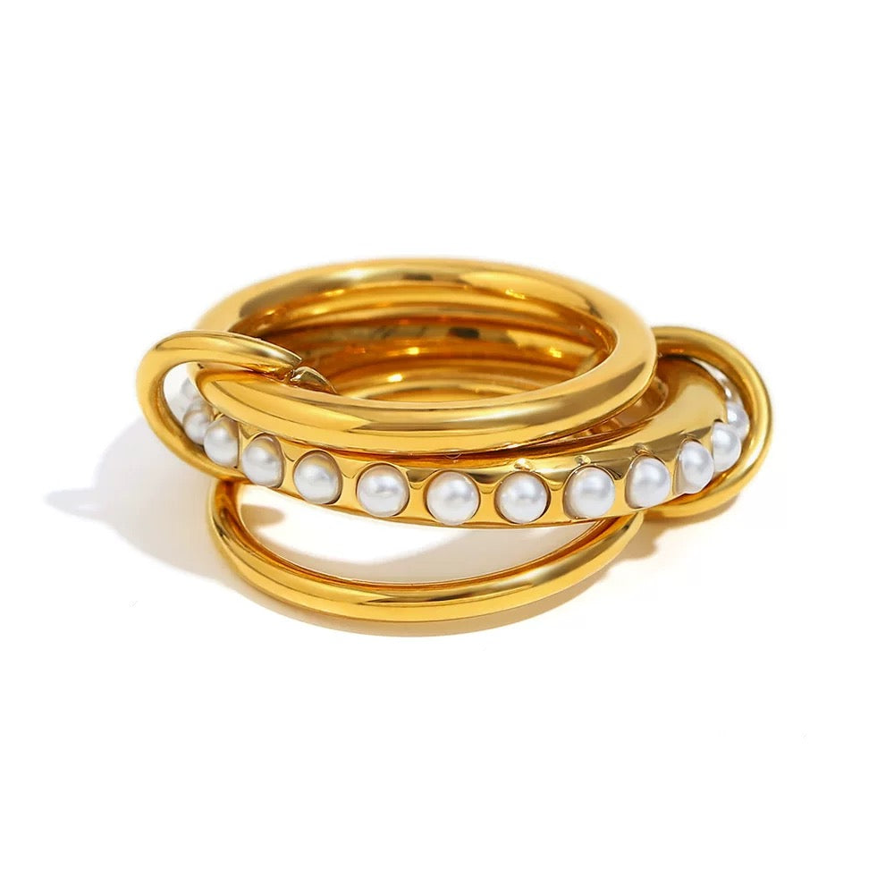 Stack of gold rings with pearl beads on a white background