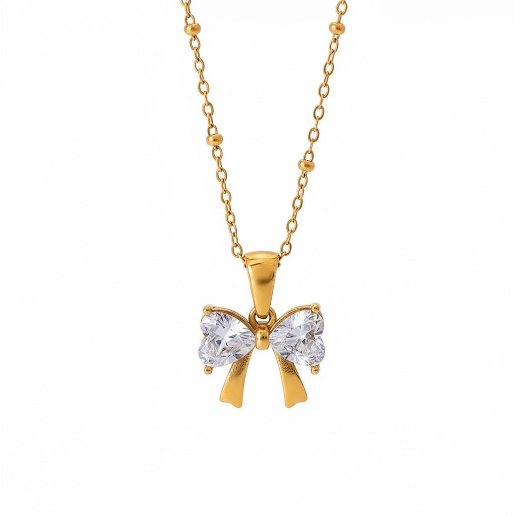 Gold bow-shaped necklace with clear stones on a white background