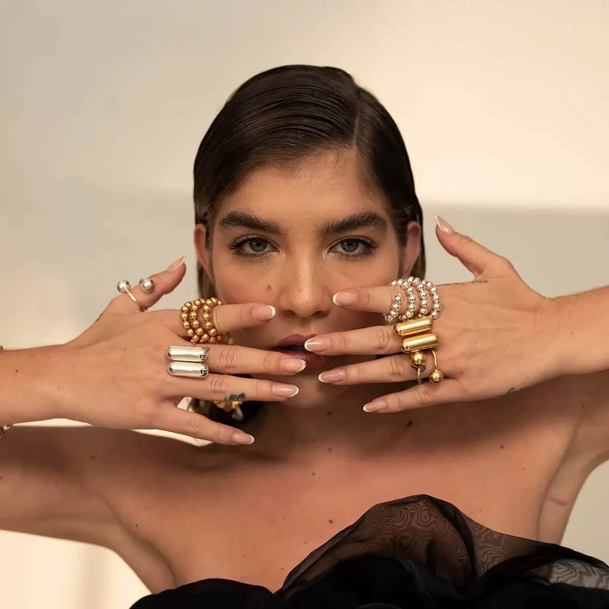 Woman wearing multiple gold rings and bracelets on her fingers and wrists.