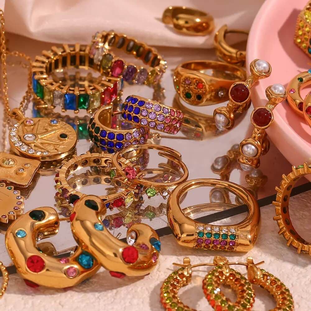 Gold jewelry with colorful gemstones on a reflective surface