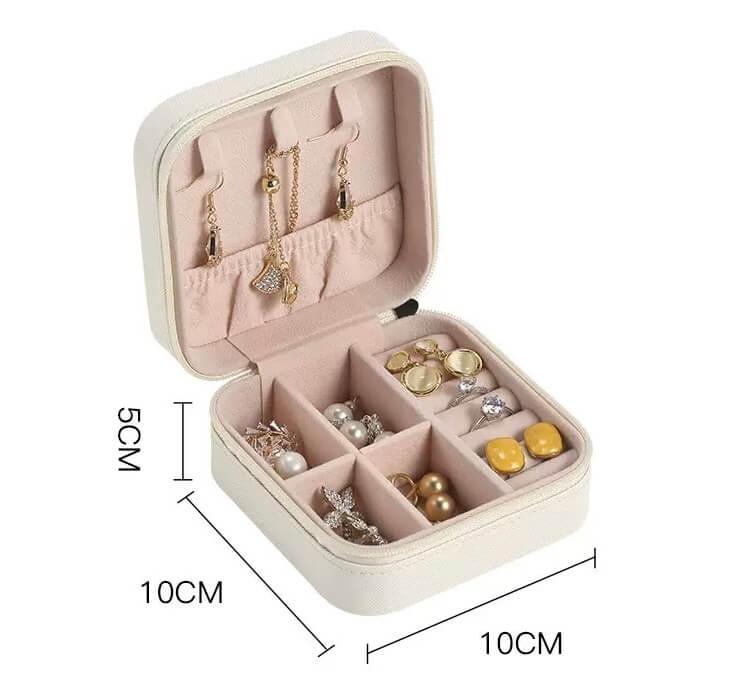 Pink jewelry box with compartments containing earrings and other accessories, with dimensions indicated.