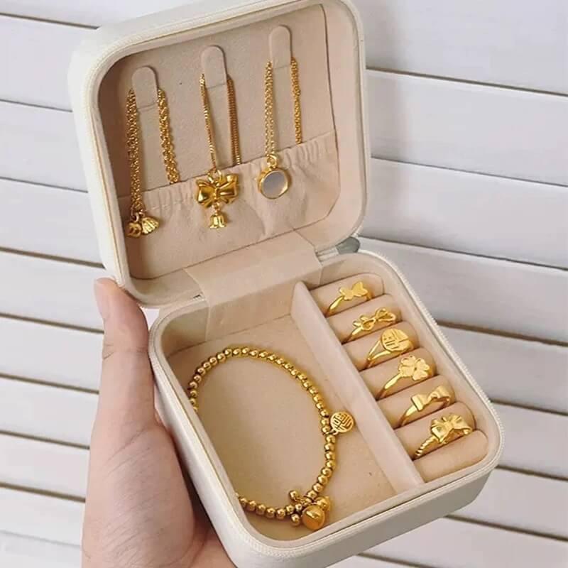 Open jewelry box with gold jewelry including necklaces, earrings, and rings on a wooden surface.