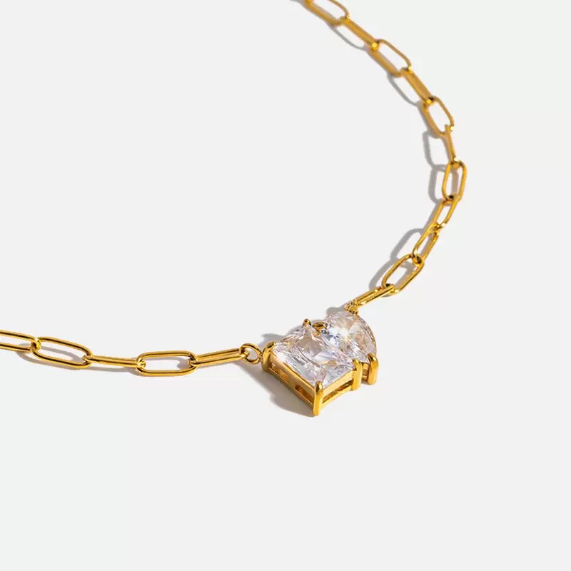 Gold necklace with a large clear gemstone on a white background