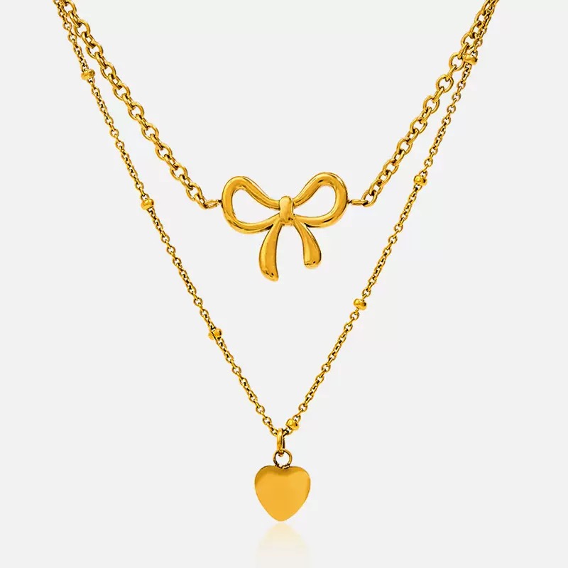 Two gold necklaces with bow and heart pendants on a white background
