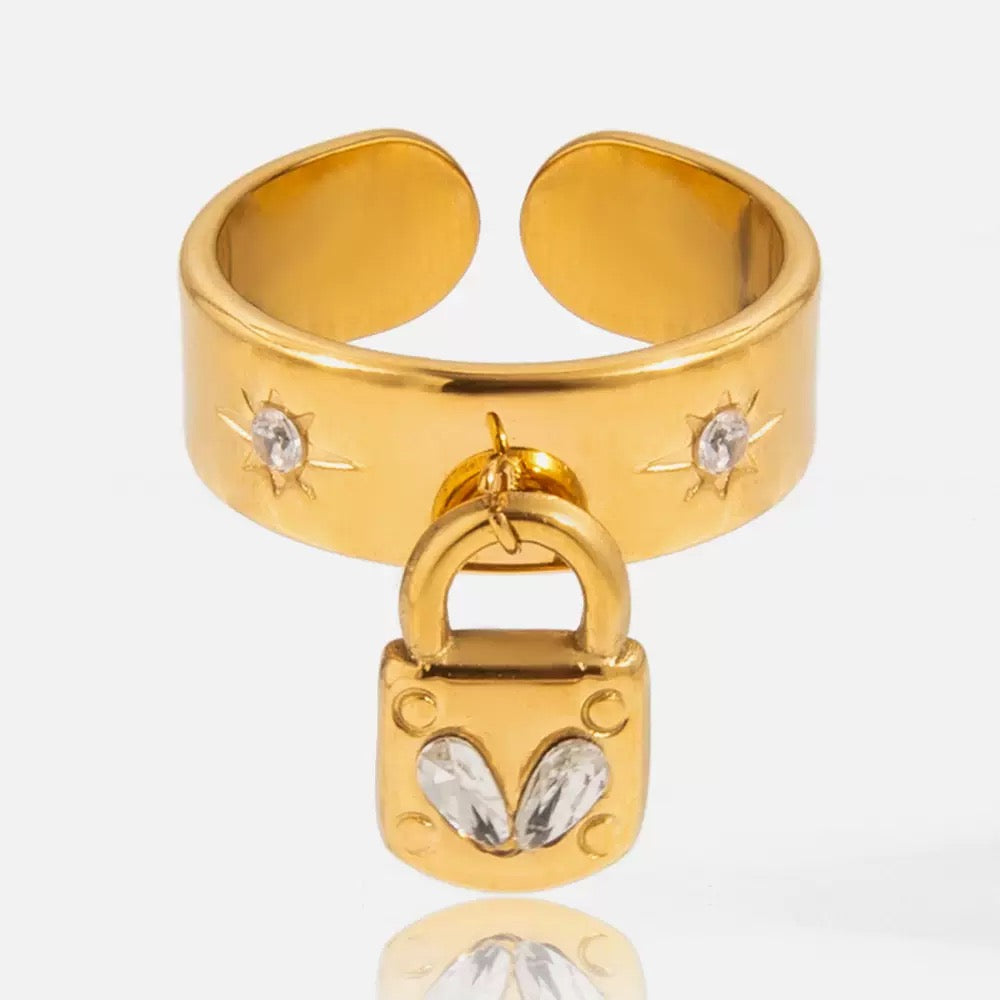 Gold ring with lock design and gemstones on a white background