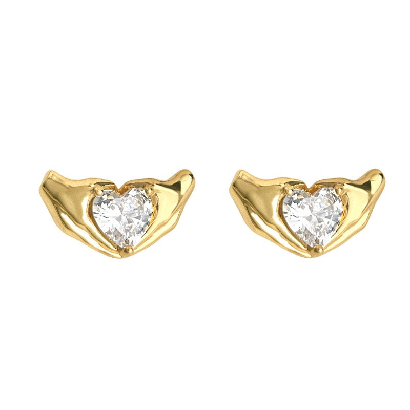 Gold heart-shaped earrings with clear gemstones on a white background