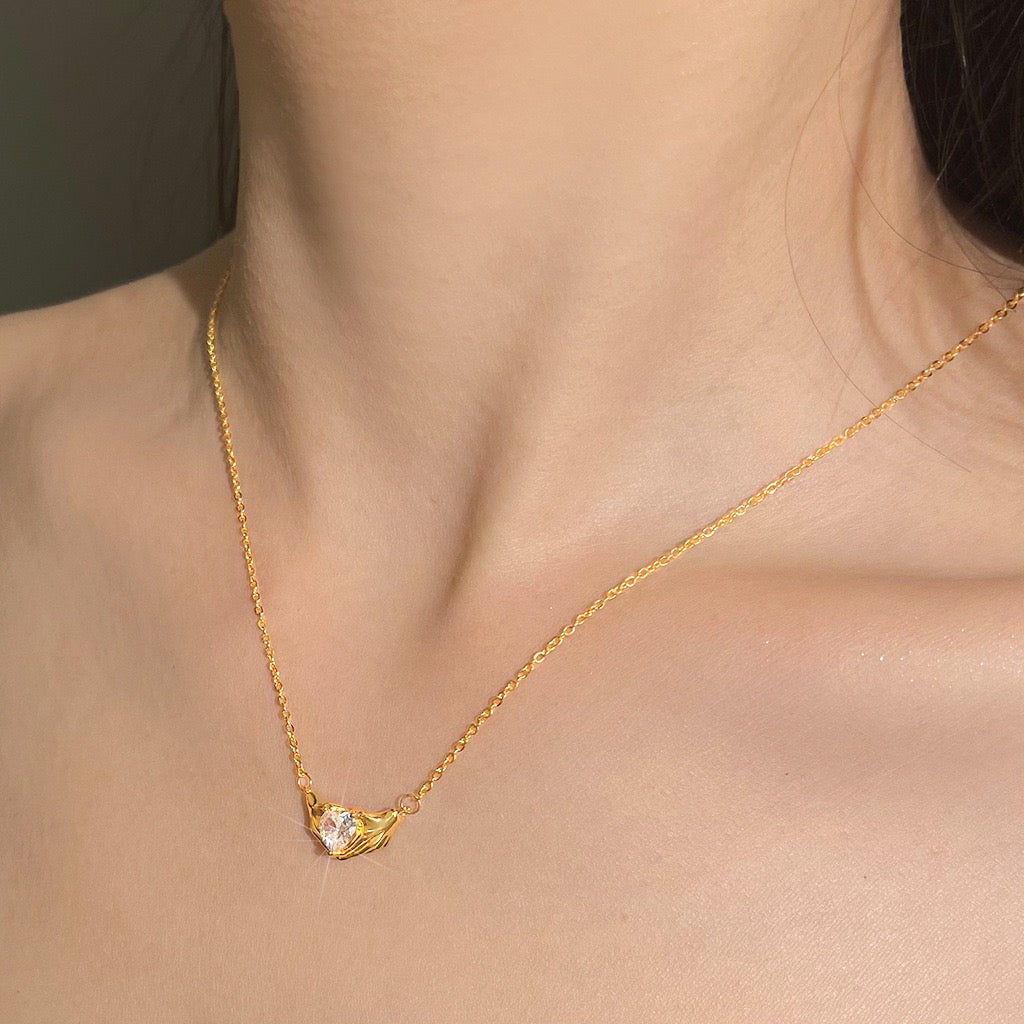Gold necklace with a heart-shaped pendant on a person's neck
