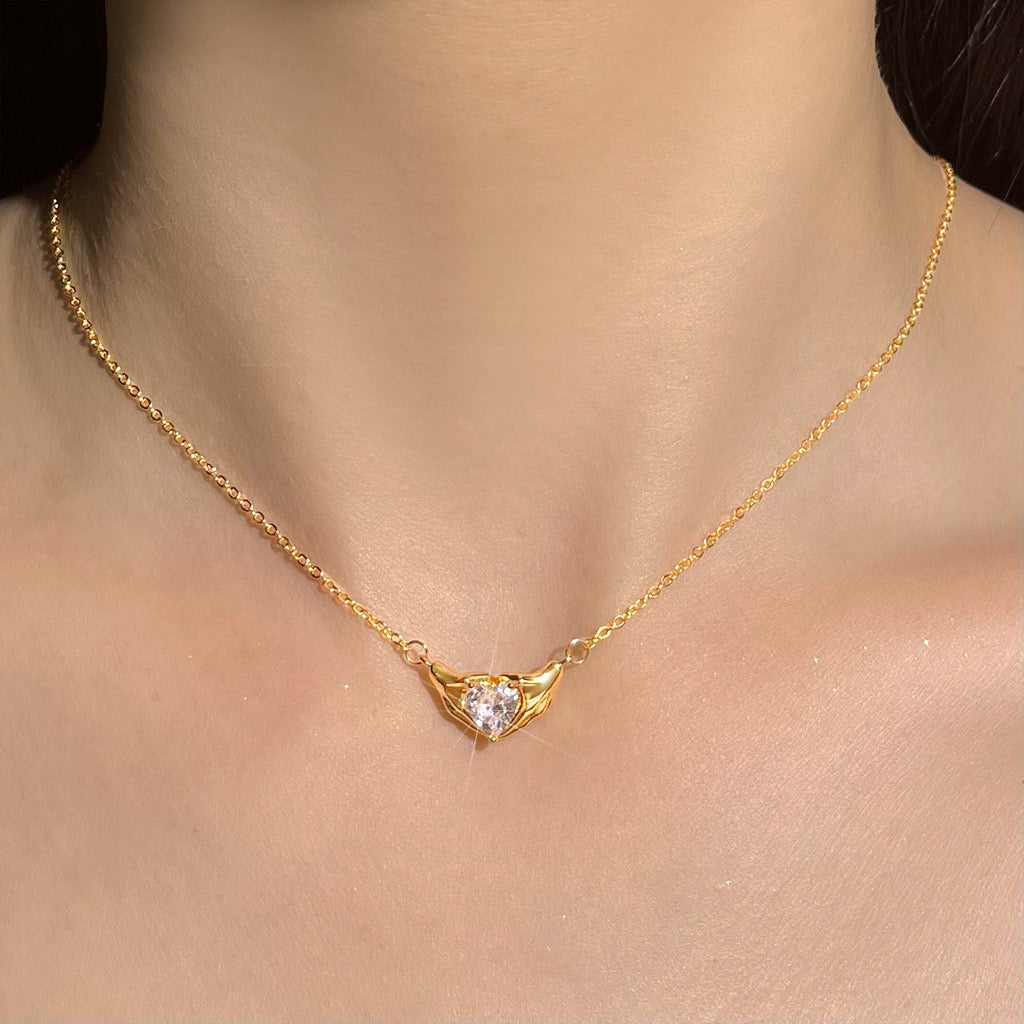 Gold necklace with a heart-shaped pendant on a person's neck