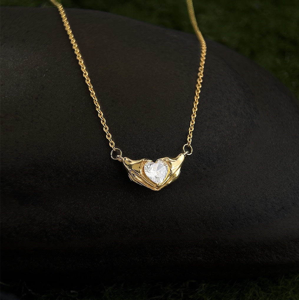 Gold necklace with a heart-shaped pendant on a dark surface