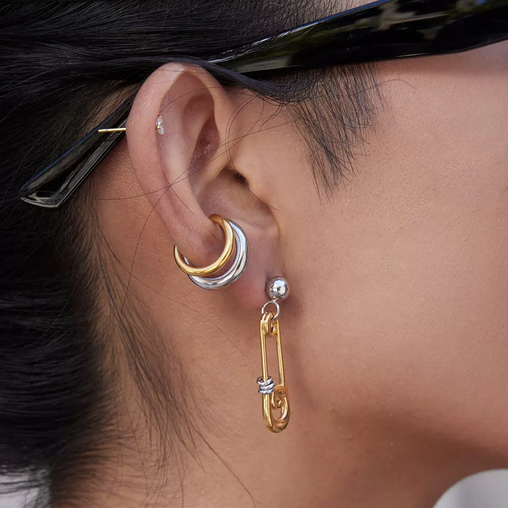 Close-up of an ear wearing gold and silver hoop earrings.