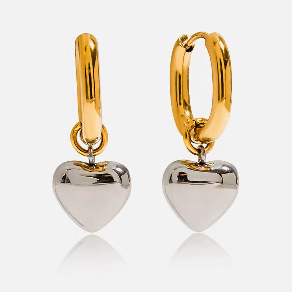Gold hoop earrings with silver heart pendants on a white background