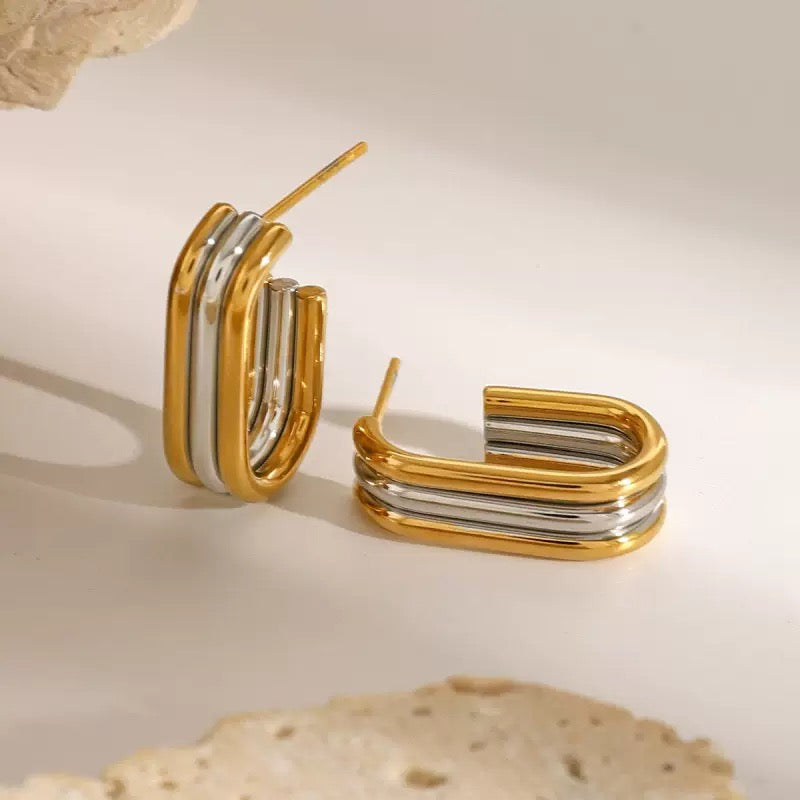 Gold and silver hoop earrings on a neutral background