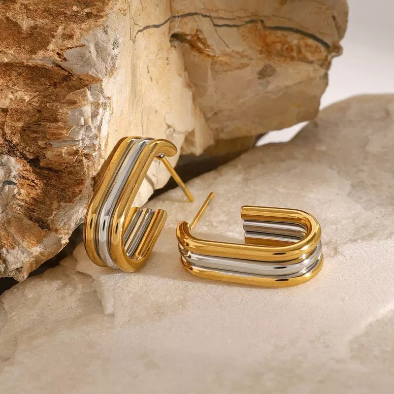 Gold and silver hoop earrings on a stone surface