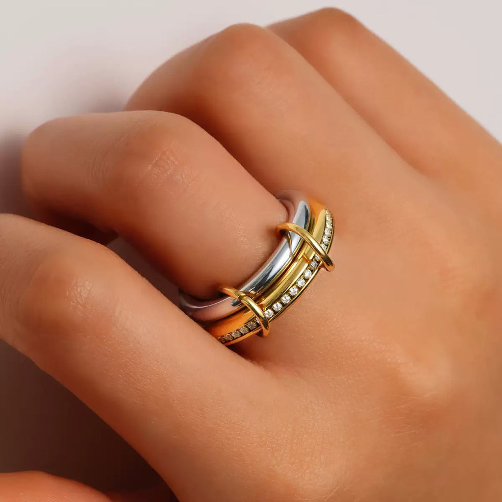 Gold and silver ring on a person's finger against a neutral background