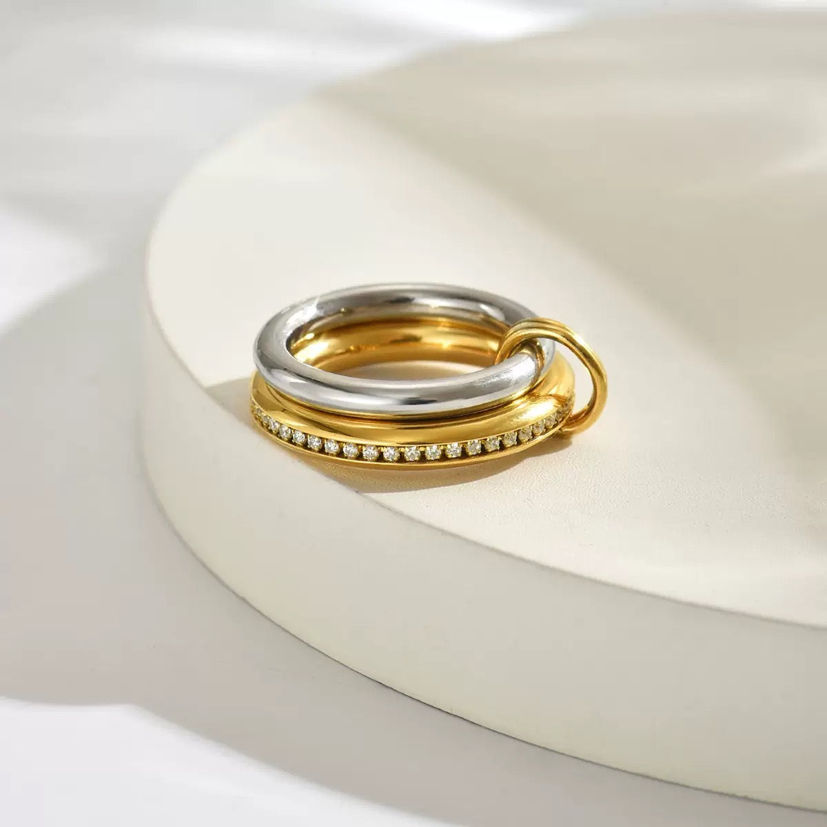 Two rings, one gold and one silver, on a white surface.