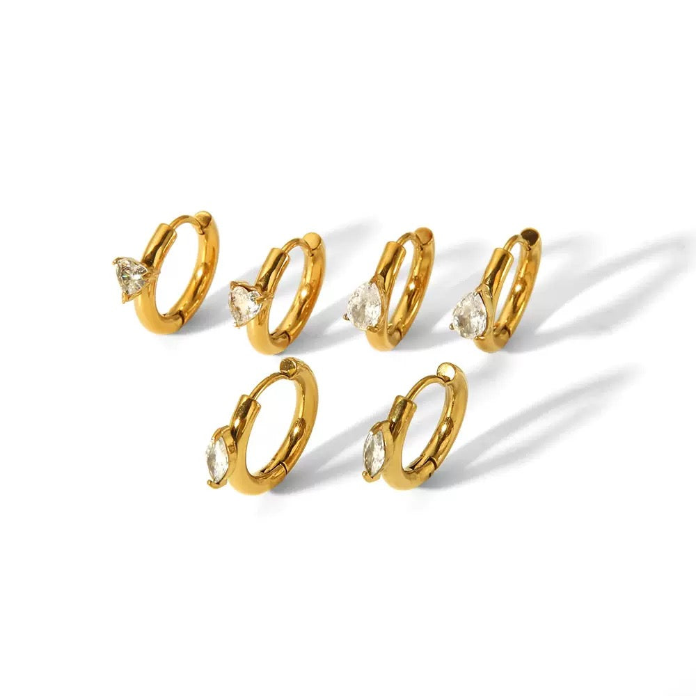 Set of gold hoop earrings with clear gemstones on a white background