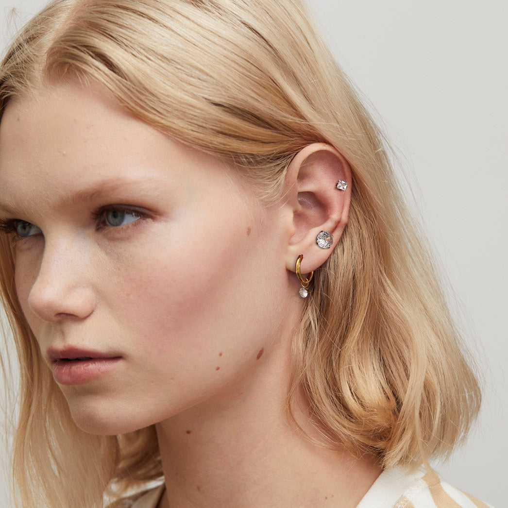 Close-up of a woman wearing earrings with a neutral background