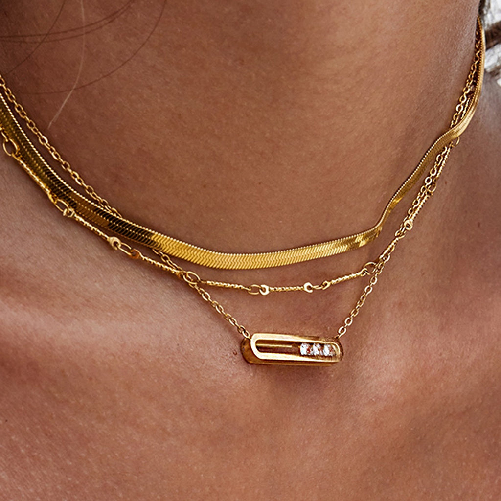Gold necklace with a bar pendant on a person's neck