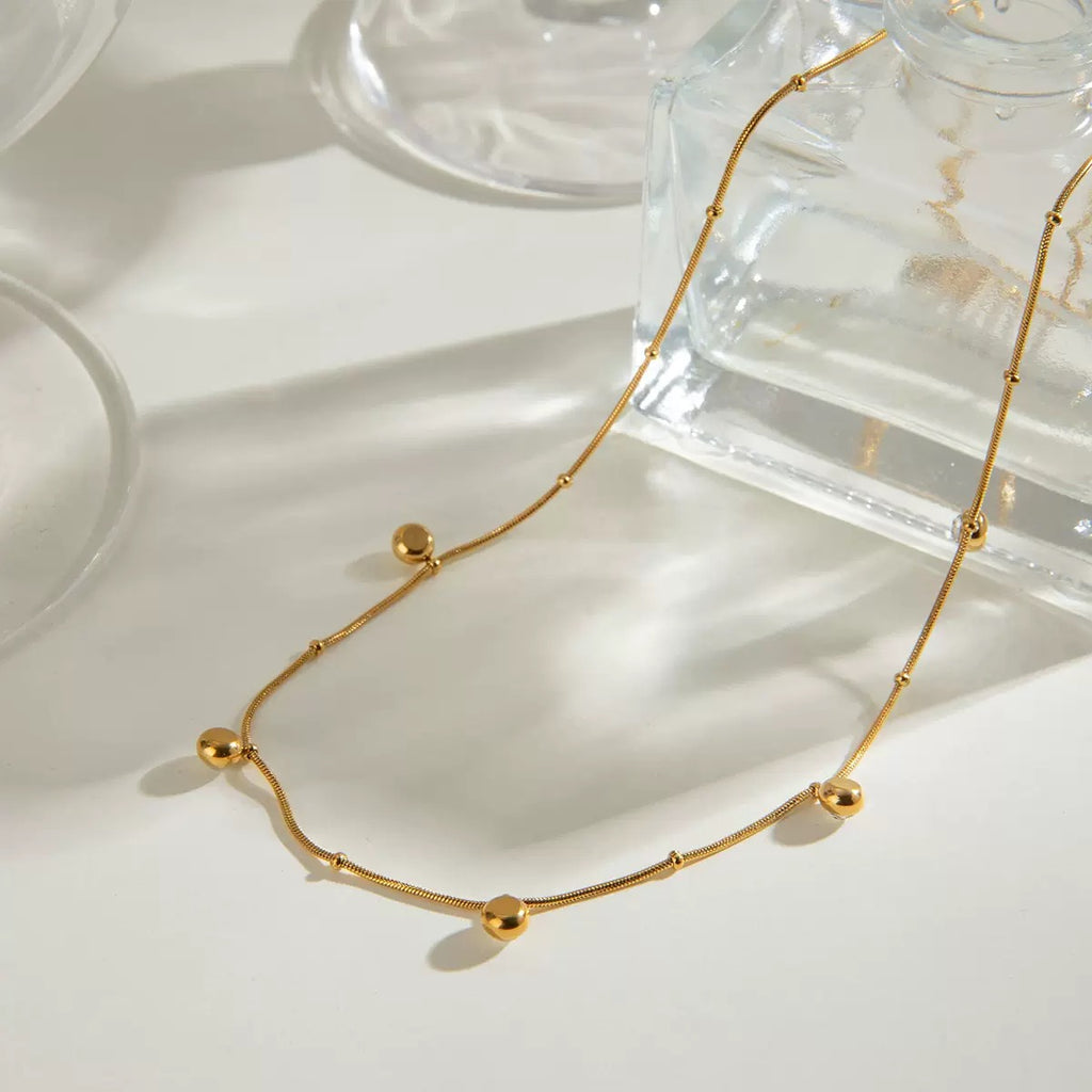 Gold necklace on a white surface with soft shadows