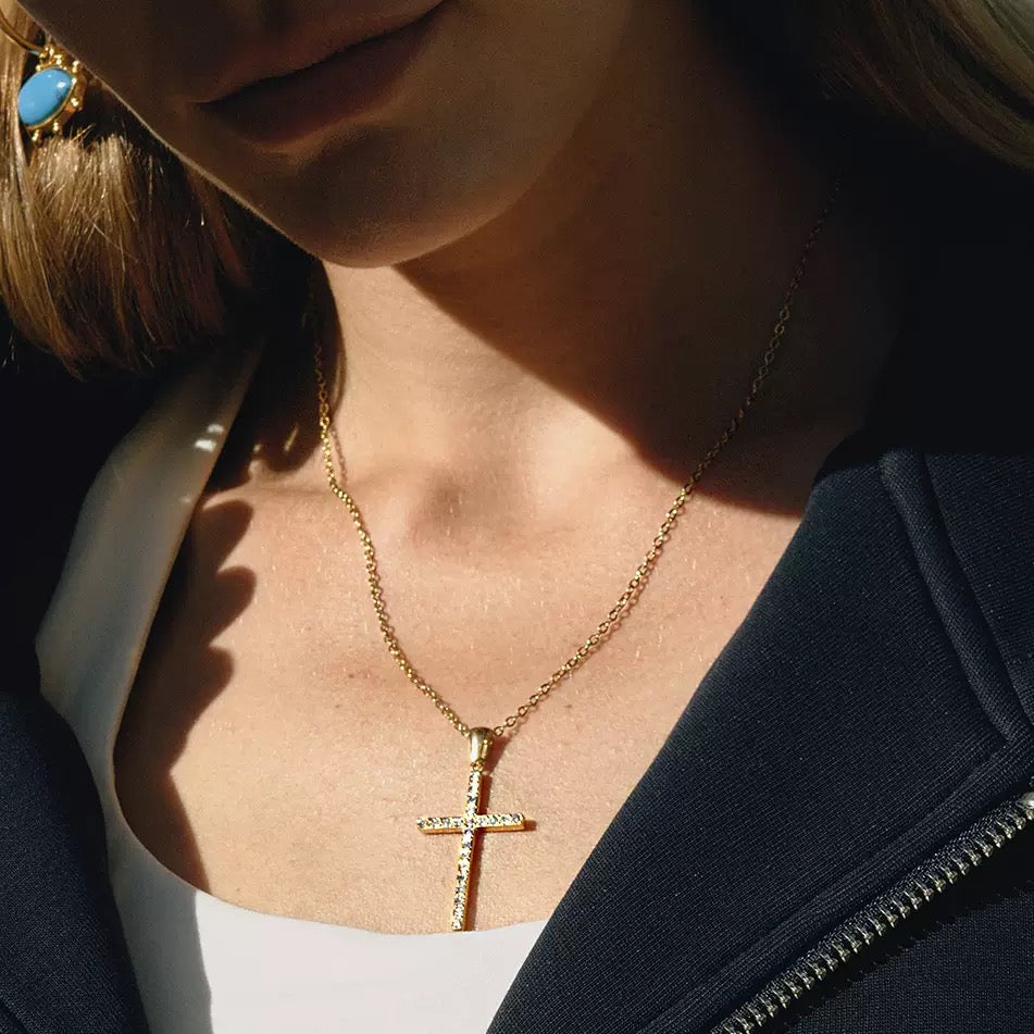Close-up of a person wearing a gold cross necklace.