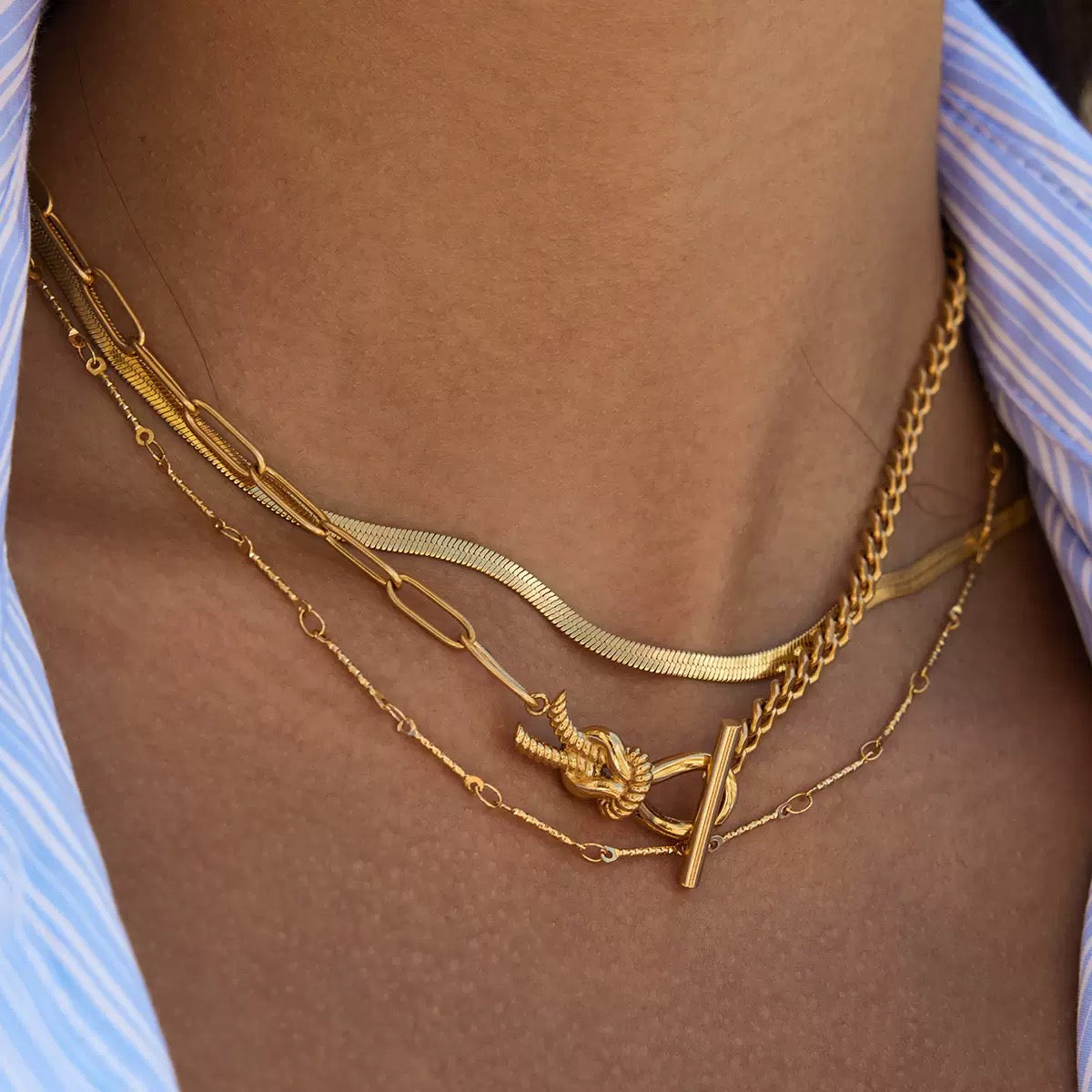 Gold necklaces on a person wearing a striped shirt