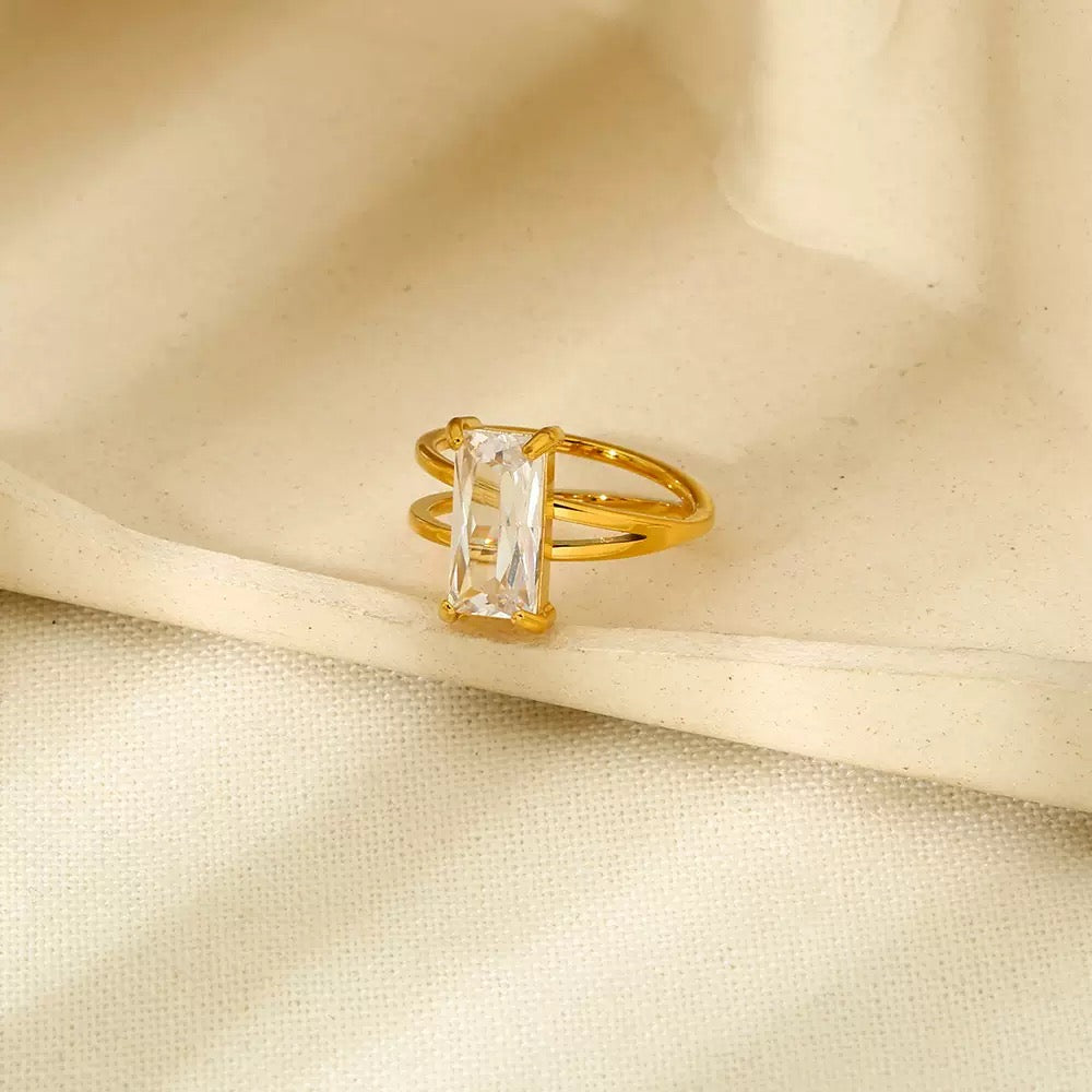 Gold ring with a clear gemstone on beige fabric