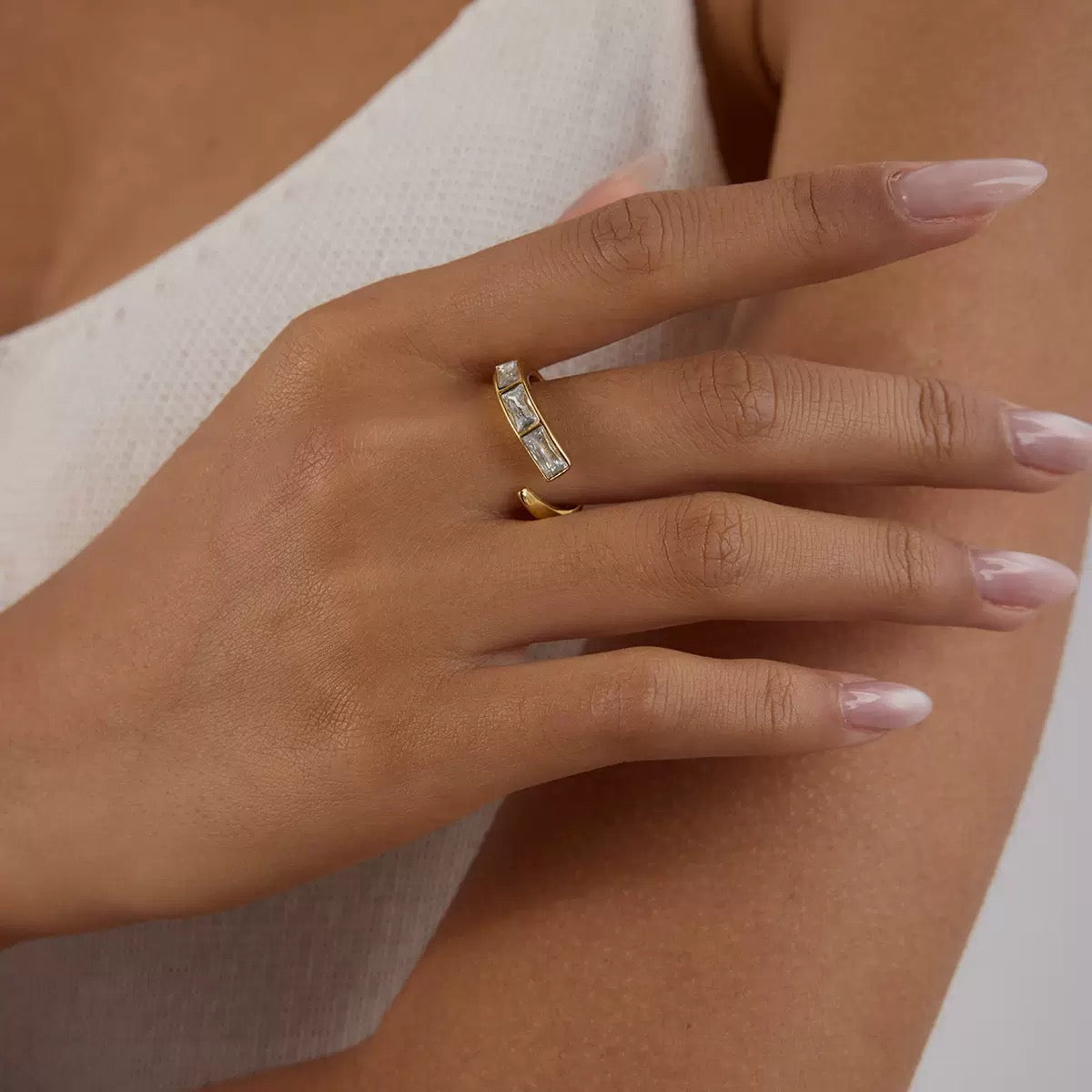 Close-up of a hand wearing two gold rings with a neutral background