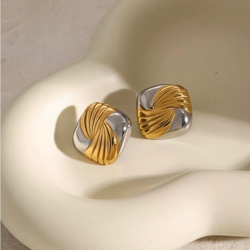 Gold and silver earrings on a beige surface