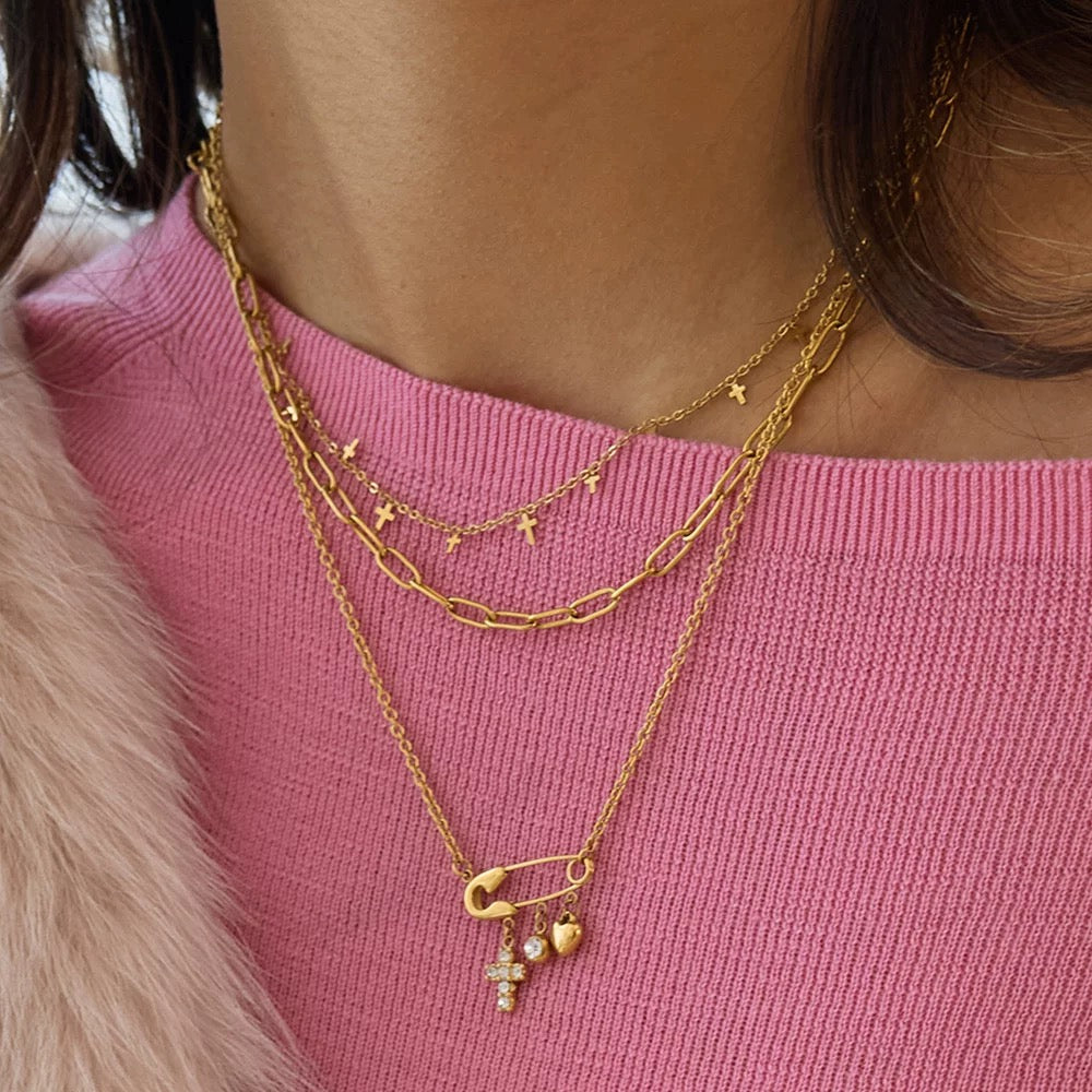 Gold necklaces with charms on a pink top