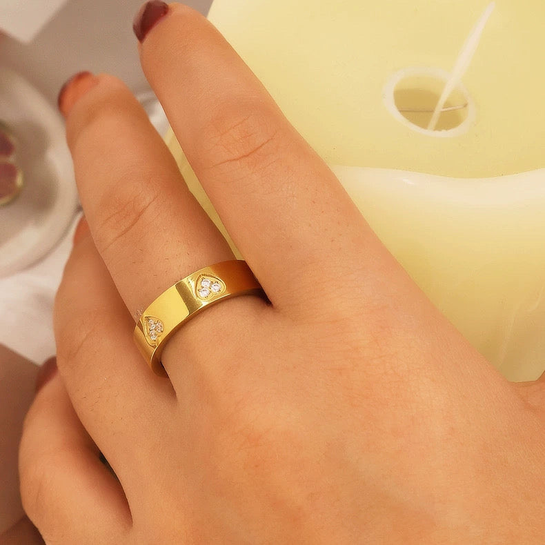 Gold ring with small diamonds on a finger against a neutral background