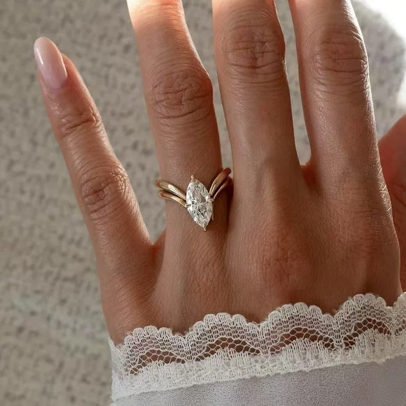 Hand wearing a diamond ring with a neutral background