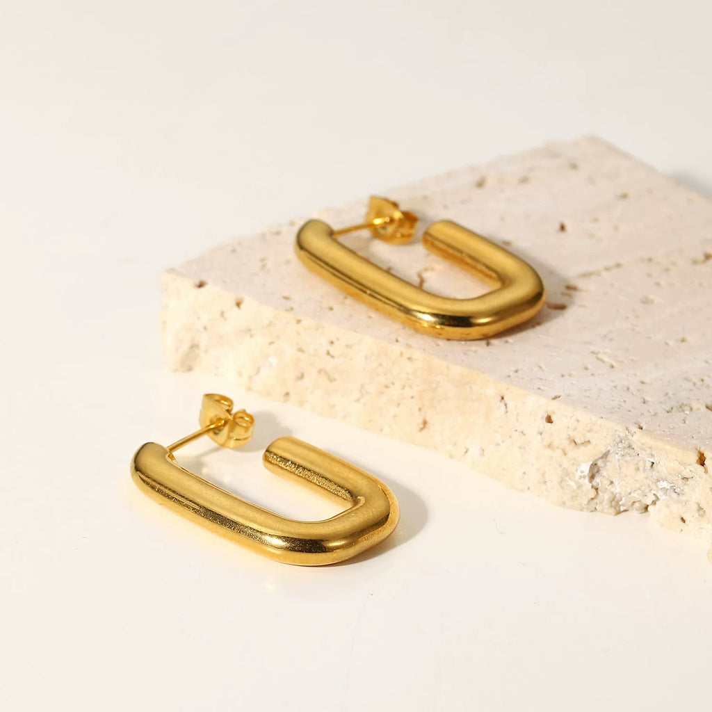Gold hoop earrings on a light stone surface