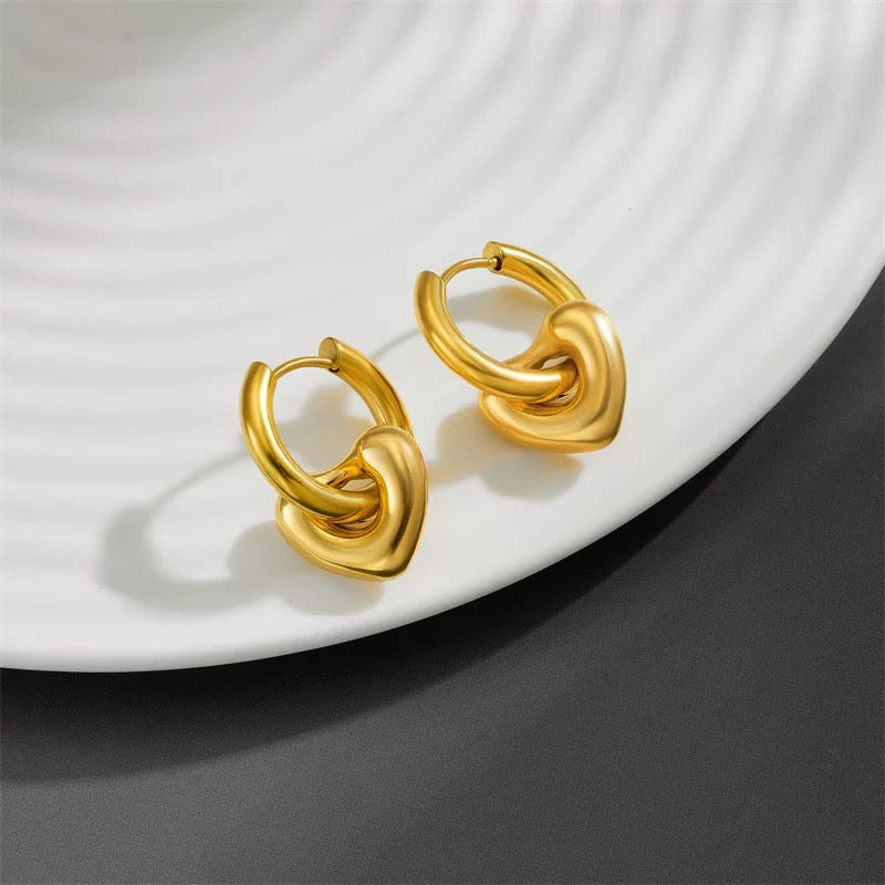 Pair of gold hoop earrings on a white plate