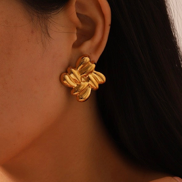 Gold earring worn by a person with a dark background