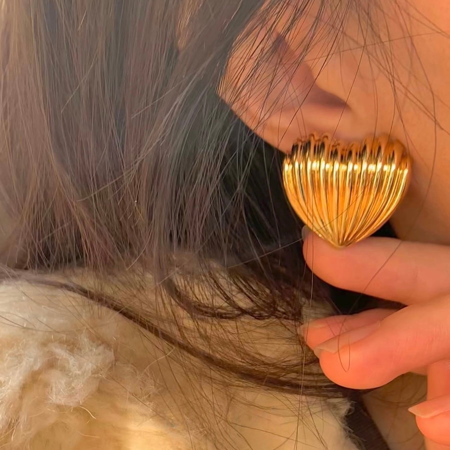 Close-up of a person wearing a gold earring with a textured design.