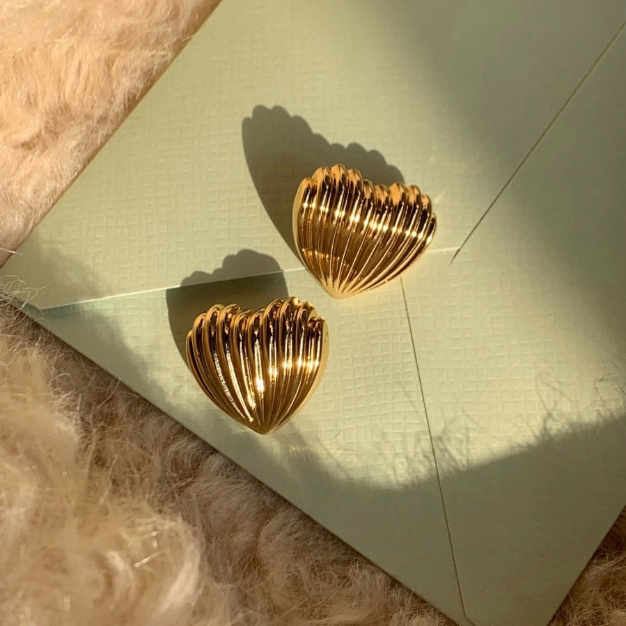 Gold heart-shaped earrings on a textured surface