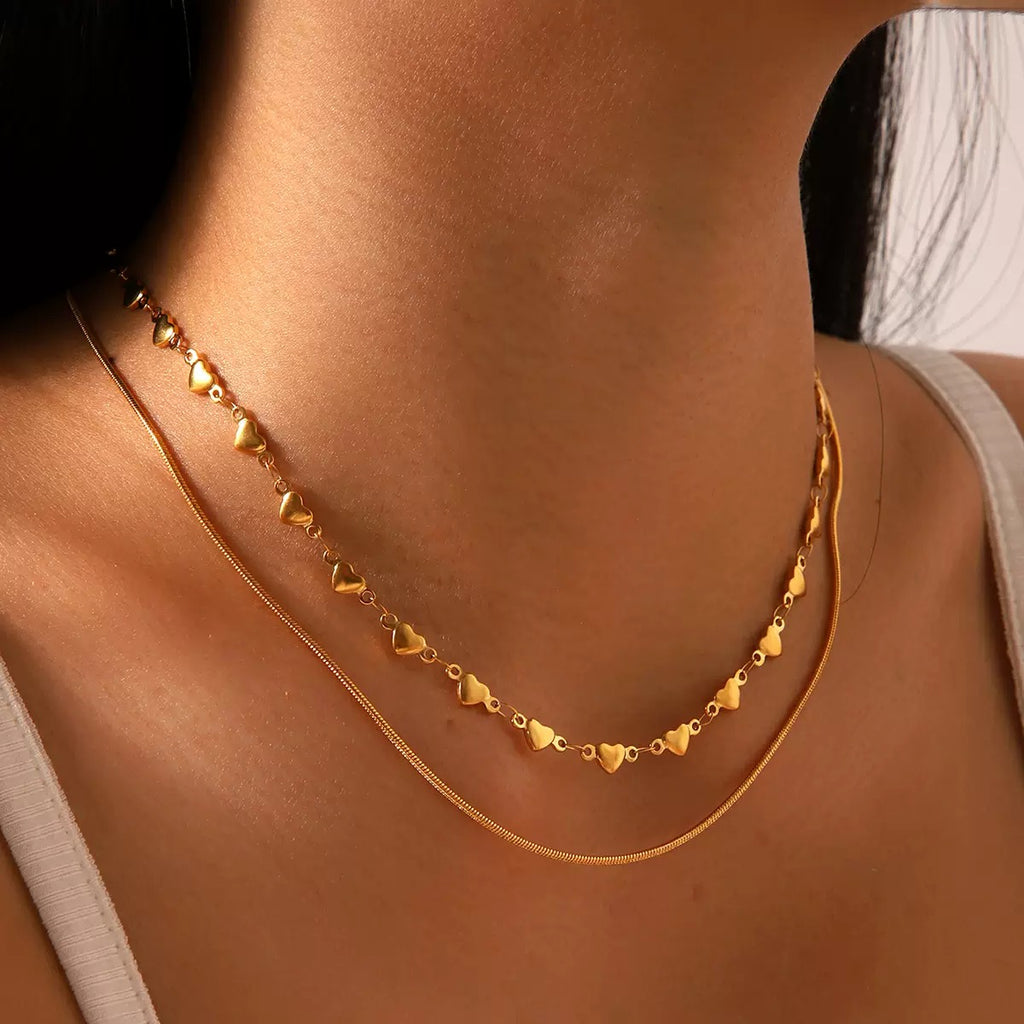 Gold necklace with heart-shaped pendants on a person's neck